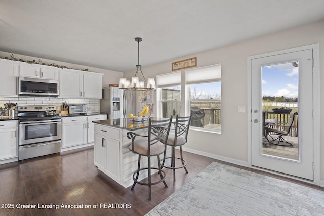 4246 Black Cherry Ln, Mason, MI 48854 - kitchen with stainless steel appliances, dark countertops, a kitchen breakfast bar, a chandelier, and white cabinetry