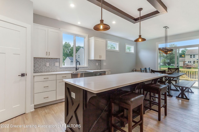 kitchen featuring backsplash, decorative light fixtures, light wood-type flooring, and a wealth of natural light