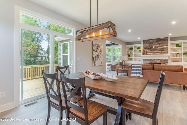 dining area with light hardwood / wood-style floors, a wealth of natural light, and a fireplace