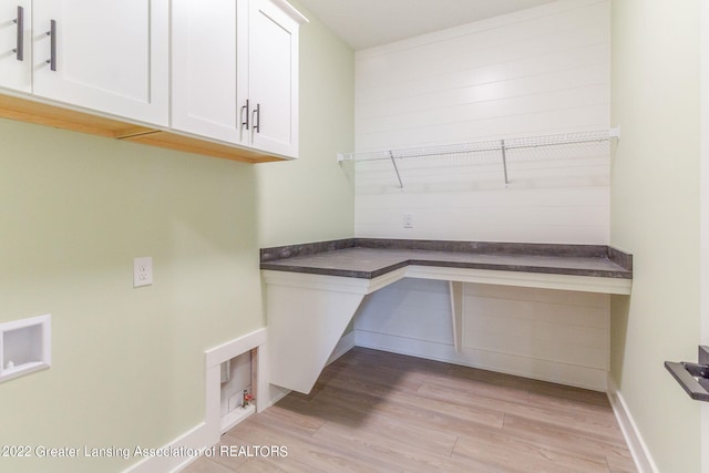 laundry area featuring washer hookup, light hardwood / wood-style flooring, and cabinets