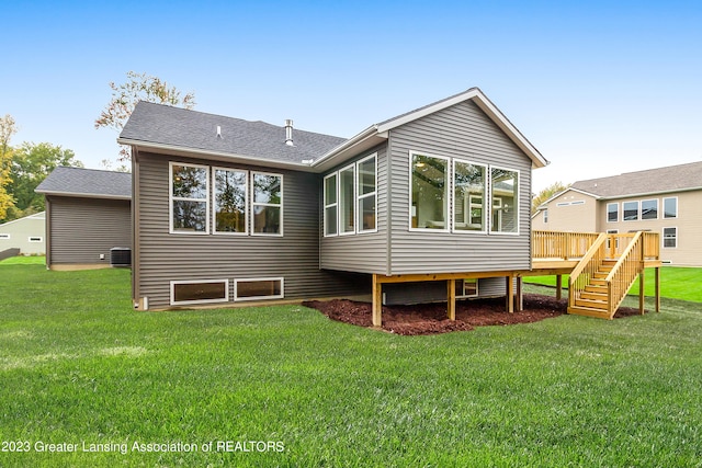 rear view of property with a deck, central AC unit, and a lawn