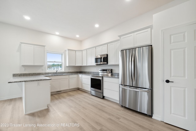 kitchen featuring light stone counters, stainless steel appliances, white cabinets, and light hardwood / wood-style flooring