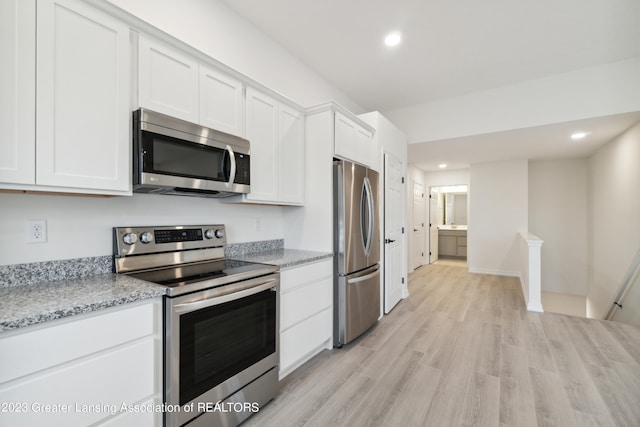 kitchen featuring white cabinets, light stone counters, light wood-type flooring, and stainless steel appliances