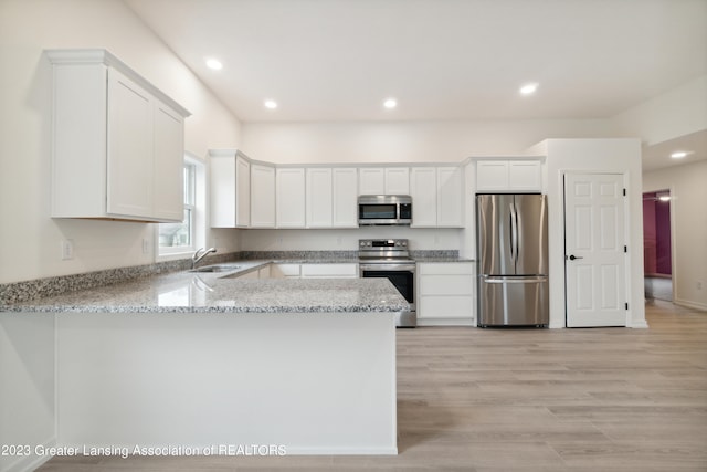 kitchen with appliances with stainless steel finishes, light stone counters, light hardwood / wood-style floors, white cabinetry, and sink