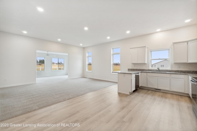 kitchen with stainless steel dishwasher, light stone countertops, light hardwood / wood-style floors, and white cabinetry