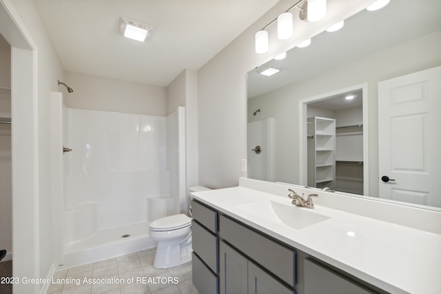 bathroom with a shower, tile floors, toilet, and vanity