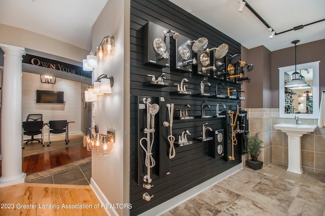 interior space with light tile floors, decorative light fixtures, rail lighting, tile walls, and decorative columns