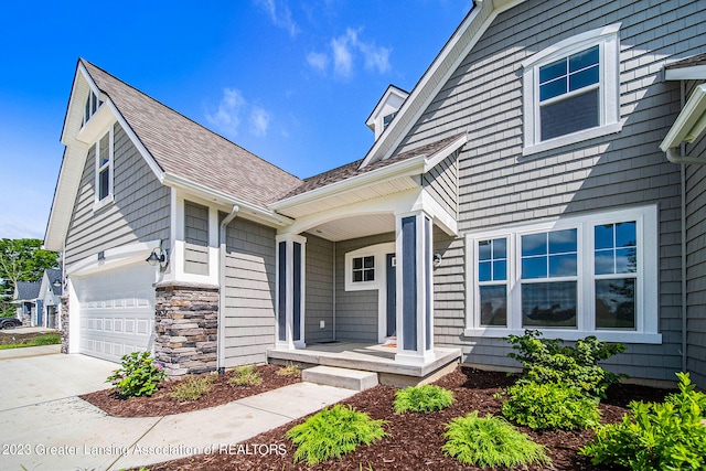 entrance to property featuring stone siding, covered porch, and concrete driveway