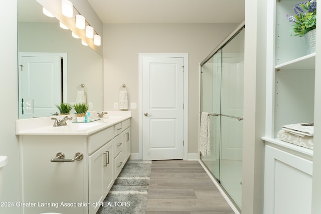 bathroom with hardwood / wood-style flooring, vanity, and a shower with shower door