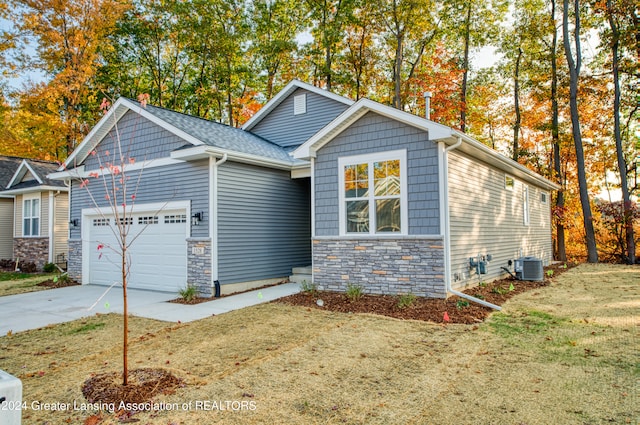 view of front of property featuring a garage, cooling unit, and a front lawn