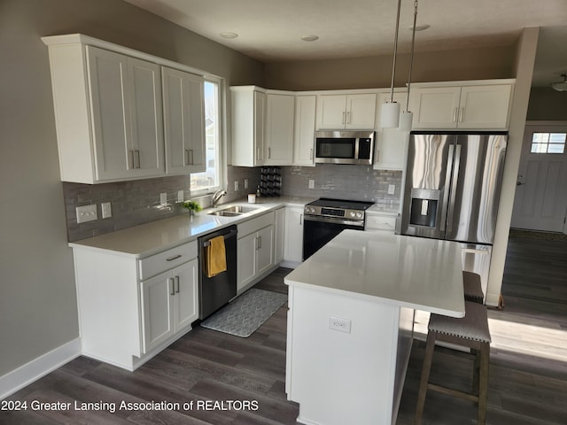 kitchen featuring pendant lighting, sink, appliances with stainless steel finishes, white cabinetry, and a kitchen island