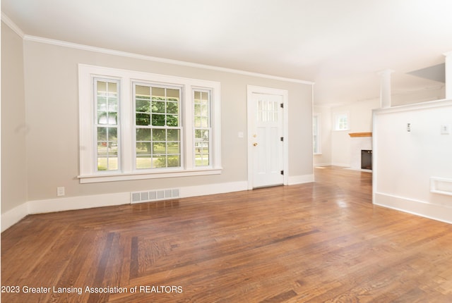 unfurnished living room featuring ornamental molding, hardwood / wood-style floors, and a fireplace