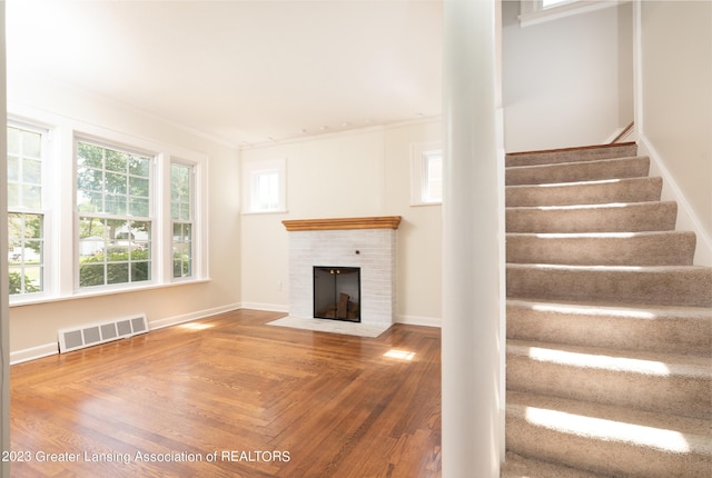 unfurnished living room with a brick fireplace and ornamental molding