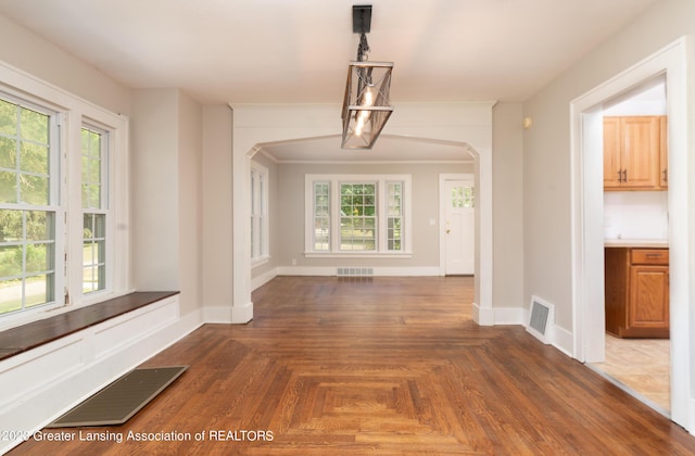 unfurnished dining area featuring plenty of natural light and dark parquet floors