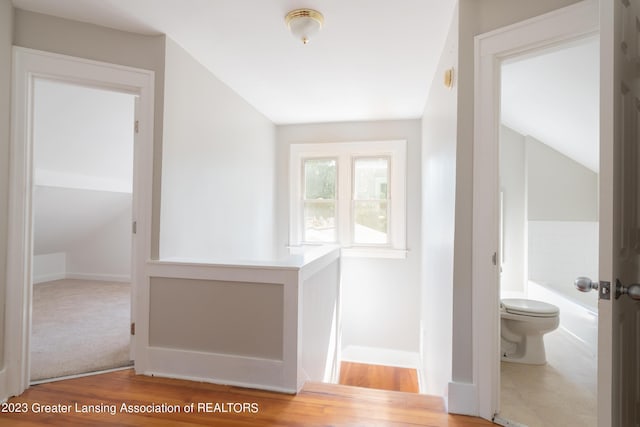 hallway with hardwood / wood-style floors and vaulted ceiling