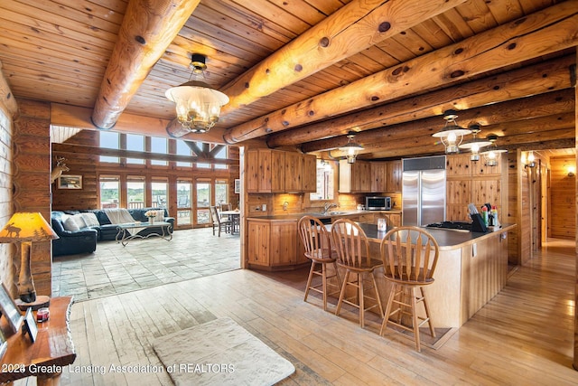 kitchen with kitchen peninsula, appliances with stainless steel finishes, a chandelier, wooden ceiling, and beam ceiling