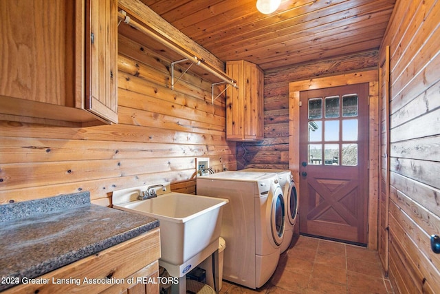 clothes washing area featuring wood ceiling, light tile flooring, wood walls, cabinets, and washing machine and dryer