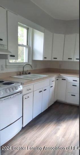 kitchen with light hardwood / wood-style floors, white cabinetry, and white range oven