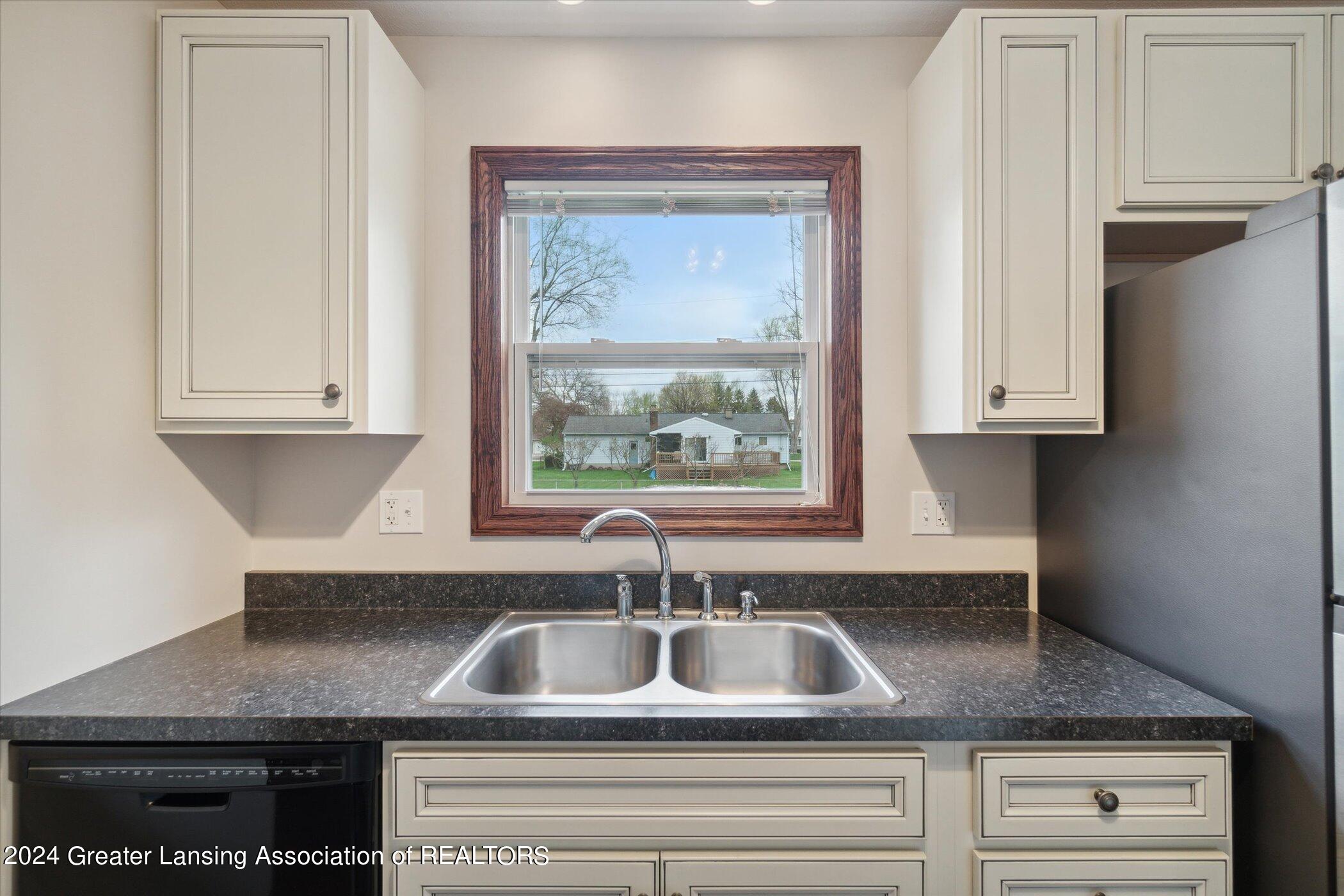 kitchen with white cabinets, sink, dishwasher, and stainless steel fridge