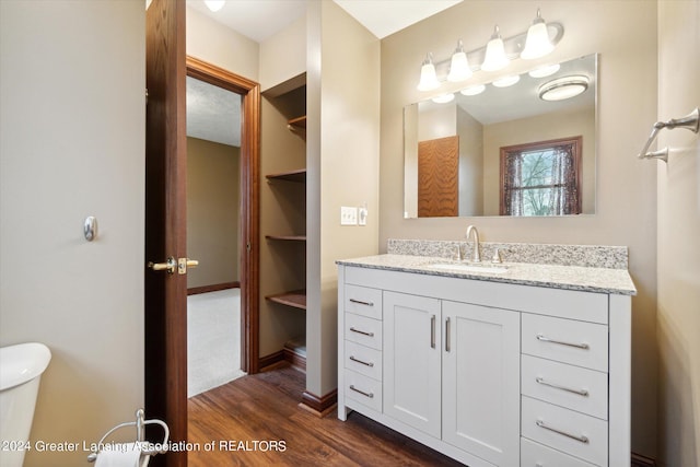 bathroom with toilet, oversized vanity, and hardwood / wood-style floors