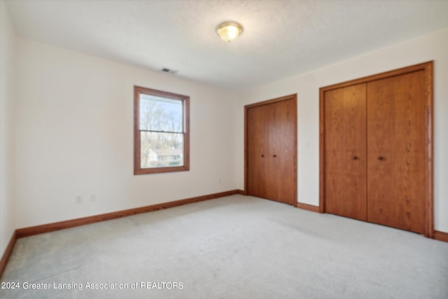 unfurnished bedroom with carpet flooring and multiple closets