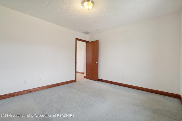 unfurnished room with carpet flooring and a textured ceiling