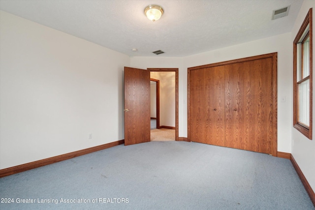 unfurnished bedroom featuring carpet flooring, a closet, and a textured ceiling