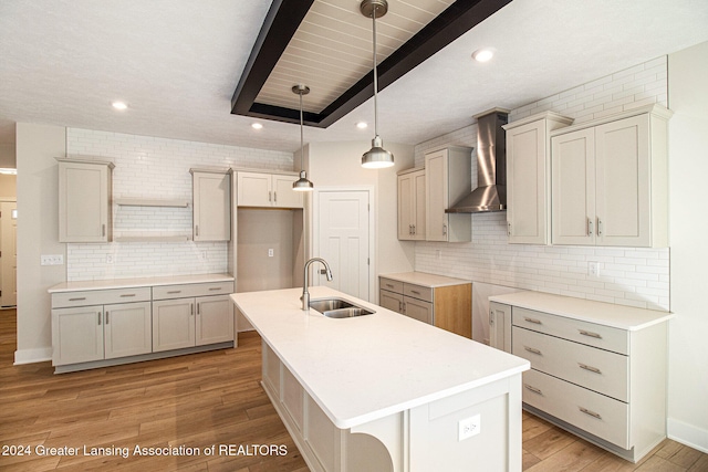 kitchen with sink, wall chimney exhaust hood, a center island with sink, and light hardwood / wood-style flooring