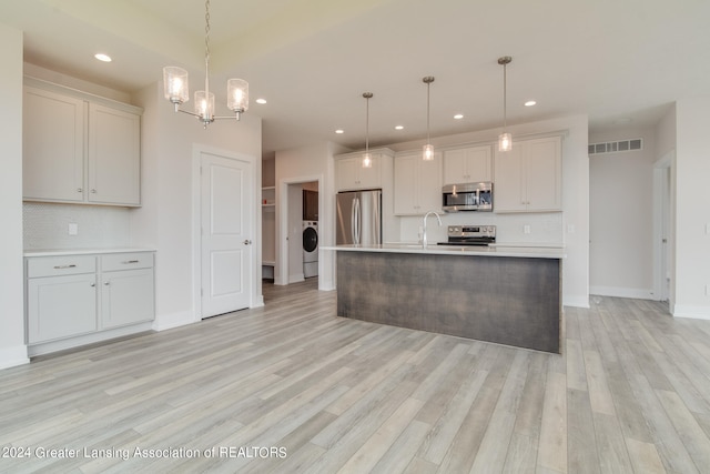 kitchen featuring stainless steel appliances, tasteful backsplash, pendant lighting, and light hardwood / wood-style flooring