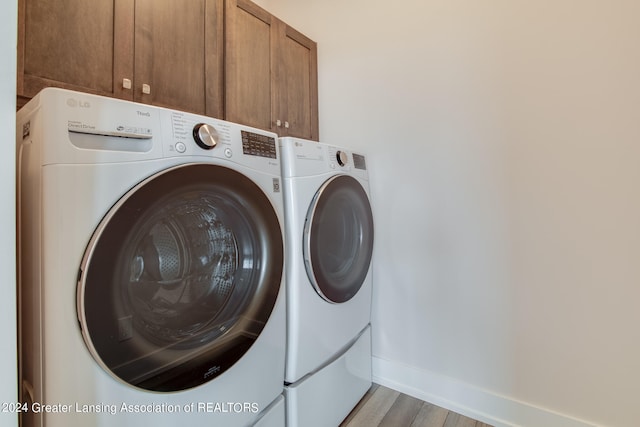 washroom featuring cabinets, wood-type flooring, and separate washer and dryer