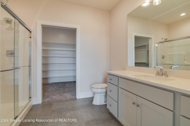 bathroom featuring oversized vanity, toilet, tile floors, and a shower with door