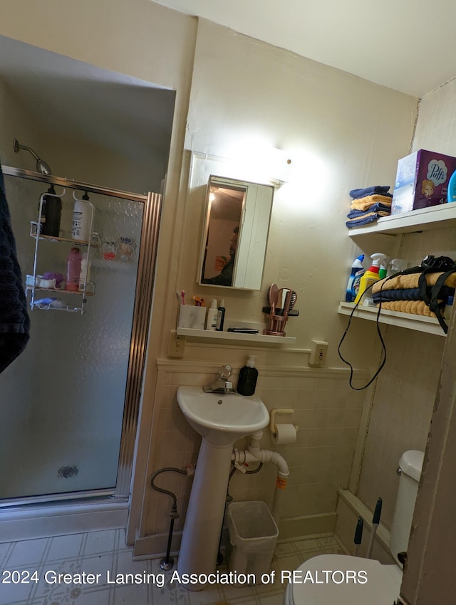 bathroom featuring tile floors, a shower with shower door, and toilet