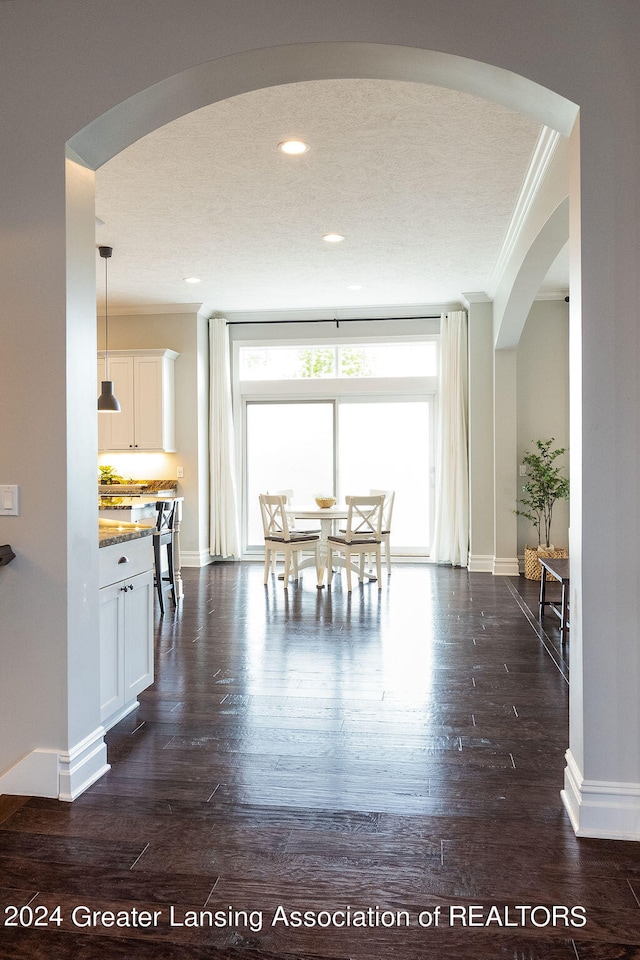 unfurnished dining area with a textured ceiling, dark hardwood / wood-style flooring, and crown molding