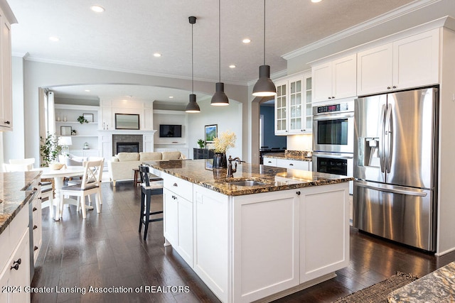 kitchen with dark stone countertops, white cabinetry, pendant lighting, and stainless steel appliances