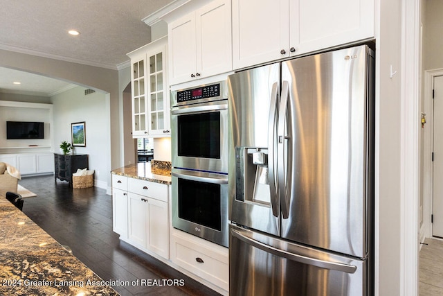 kitchen with dark hardwood / wood-style flooring, stainless steel appliances, light stone counters, and white cabinetry