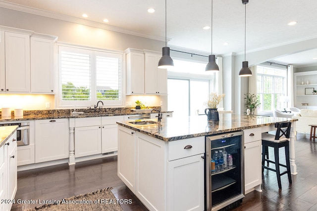 kitchen with a center island with sink, pendant lighting, white cabinets, and wine cooler