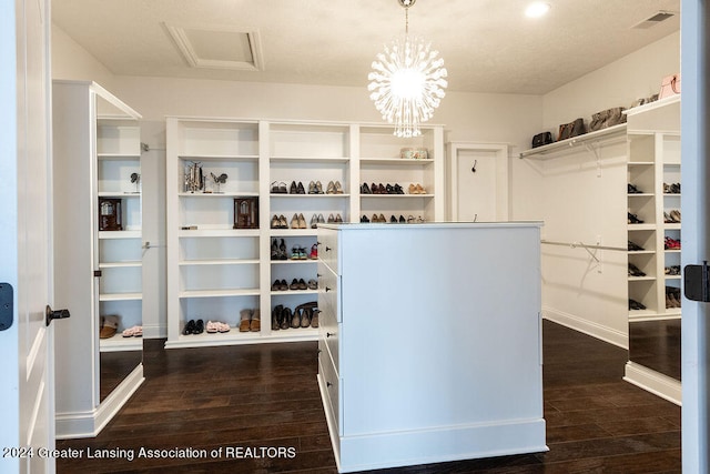 spacious closet featuring dark hardwood / wood-style flooring and a chandelier