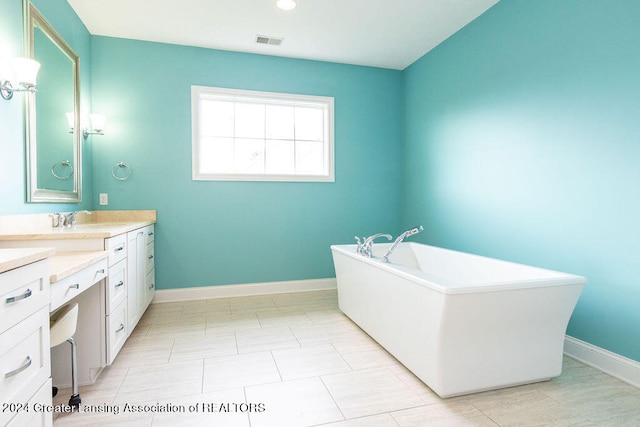 bathroom with a bath, vanity, and tile patterned floors