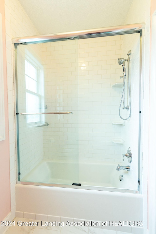 bathroom featuring combined bath / shower with glass door