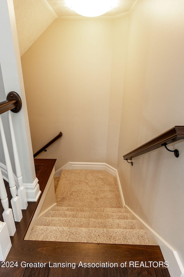 stairs featuring a textured ceiling and vaulted ceiling