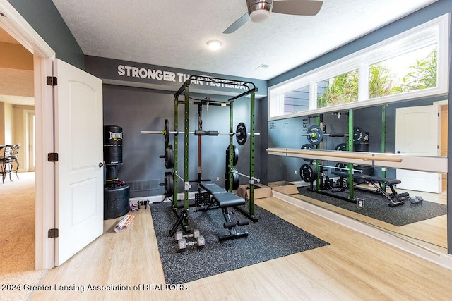 workout room with wood-type flooring, a textured ceiling, and ceiling fan