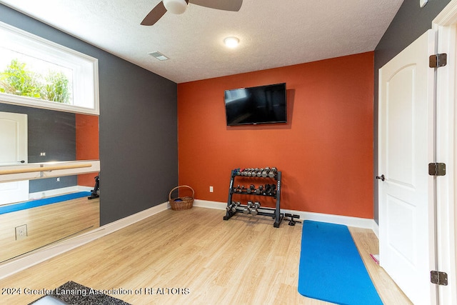 workout area with ceiling fan, a textured ceiling, and hardwood / wood-style flooring