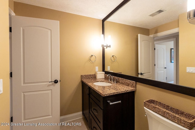 bathroom featuring tile patterned flooring, vanity, a textured ceiling, and toilet