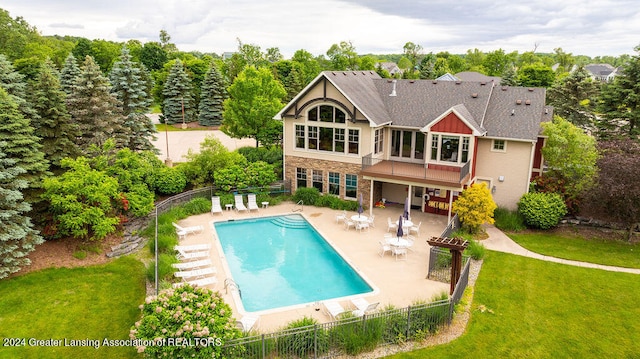 back of property with a patio, a fenced in pool, and a lawn