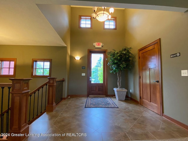 entryway featuring plenty of natural light, a towering ceiling, and a notable chandelier