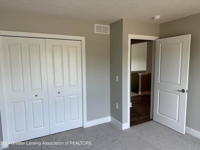 unfurnished bedroom featuring a textured ceiling, a closet, and light wood-type flooring