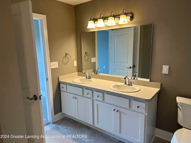 bathroom featuring double sink, toilet, tile floors, and large vanity