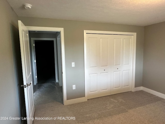 unfurnished bedroom with a closet, a textured ceiling, and carpet floors