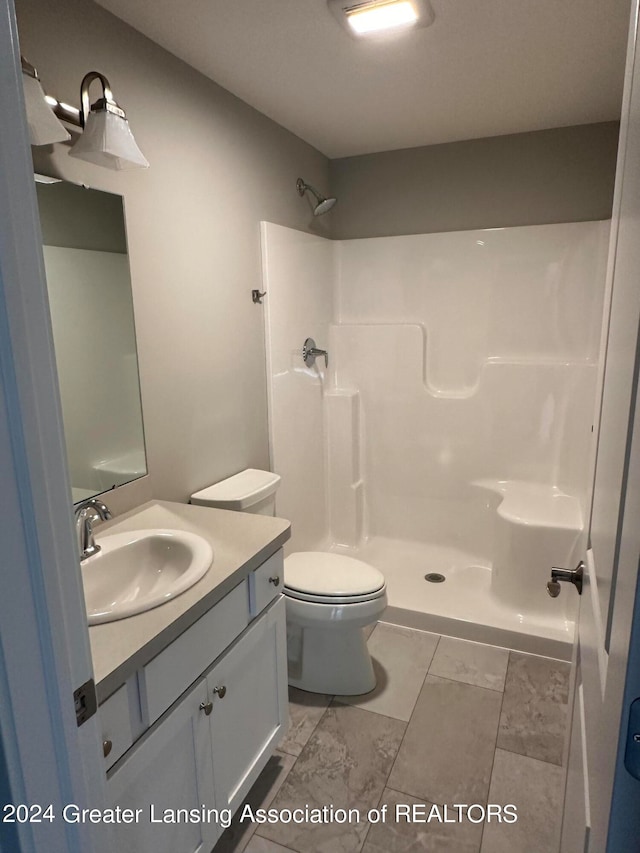 bathroom with tile flooring, vanity, toilet, and a shower