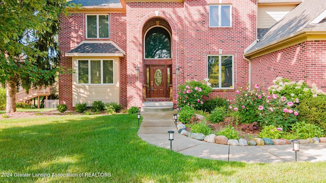 entrance to property with brick siding, a lawn, and a shingled roof